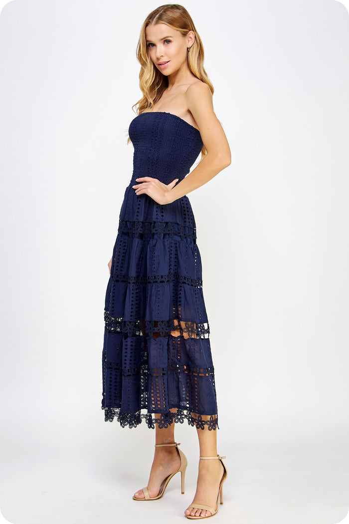 Woman wearing a navy strapless dress with lace details on a white background