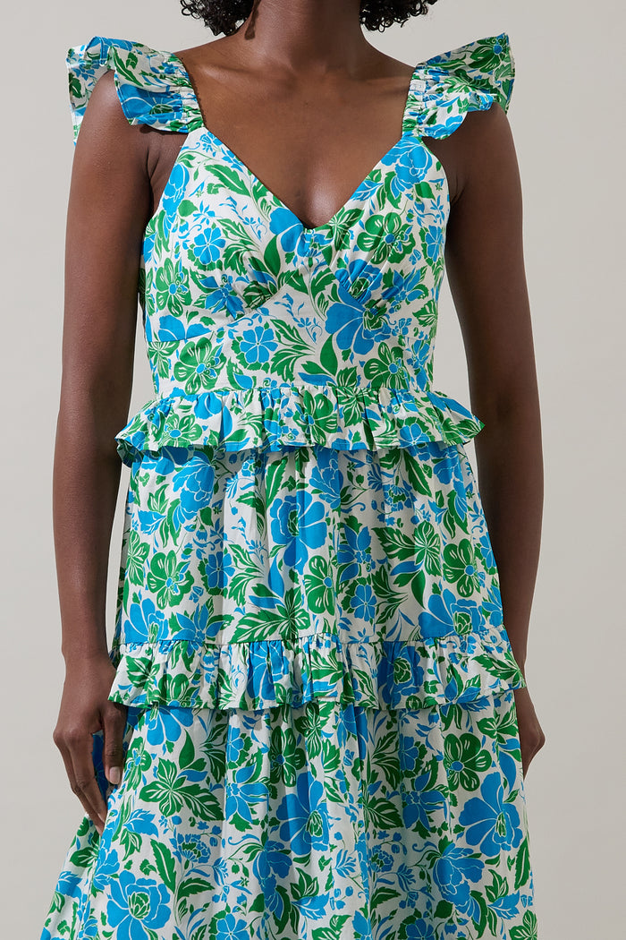 Woman wearing a blue floral dress with leg slit and puffy straps against a plain background