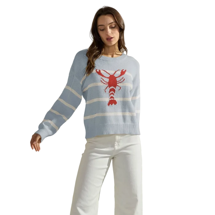 Woman wearing a light blue sweater with a red lobster design against a neutral background