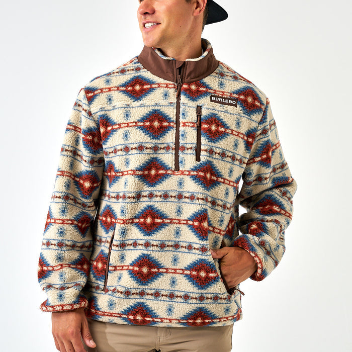 Person wearing a patterned pullover with visible branding on a white background