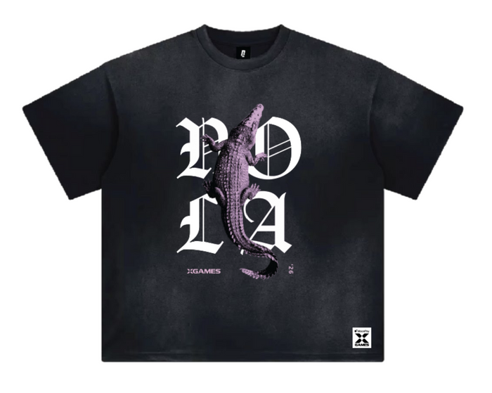 A black short-sleeve t-shirt with a graphic print featuring a crocodile over the letters 'NOLA' in white gothic font, with 'XGAMES '26' printed below.