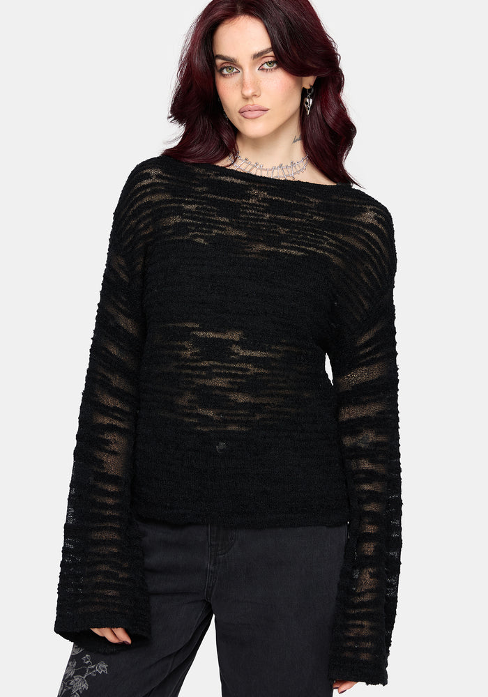 Woman wearing a black distressed jumper with long sleeves and back denim jeans on a white background