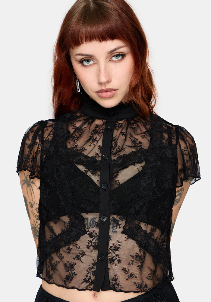 Woman wearing a black lace top against a plain background