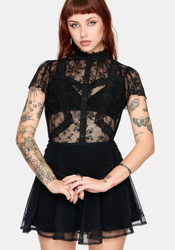 Woman wearing a black lace top and mini skirt on a white studio background