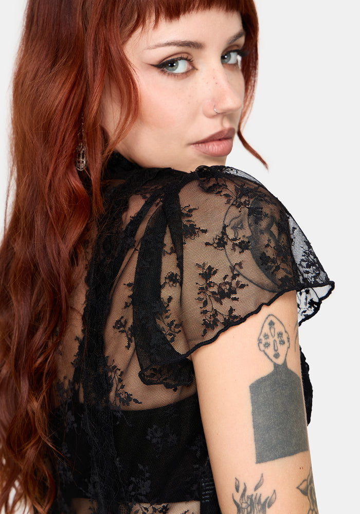 Woman wearing a black lace top against a white studio background