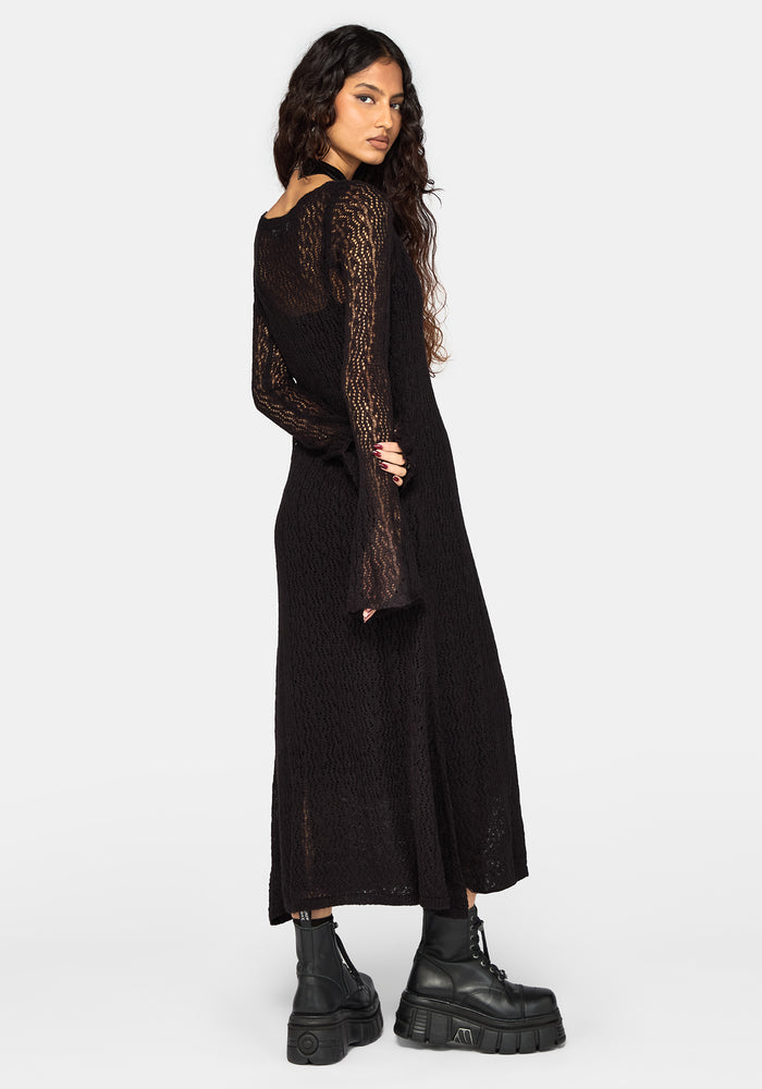 A woman modeling a black long-sleeve knit cardigan with sheer sleeves, shown from the back against a light gray studio background.