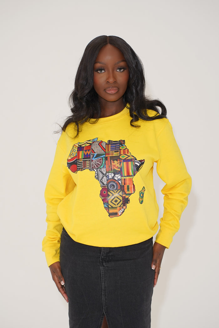 A person wearing a yellow sweatshirt with a colorful geometric pattern in the shape of the African continent.