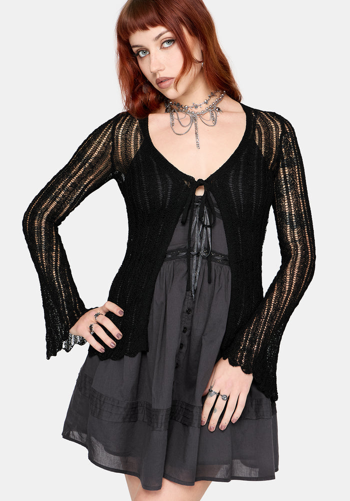 Women's black long sleeve distressed cardigan with v-neckline and self tie function at chest, against a white studio background