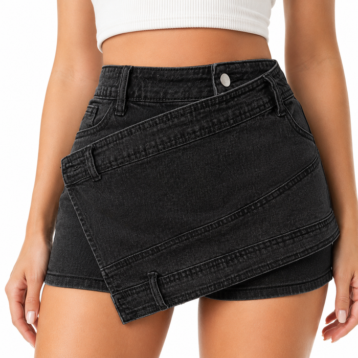 Close-up of women's asymmetric black denim skort showing the wrap panel, denim texture, stitching, belt loops and button detail.