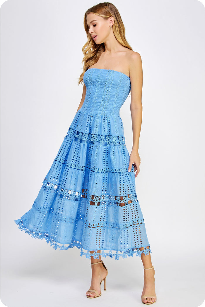 Woman wearing a light blue strapless dress with ruffled layers on a white background