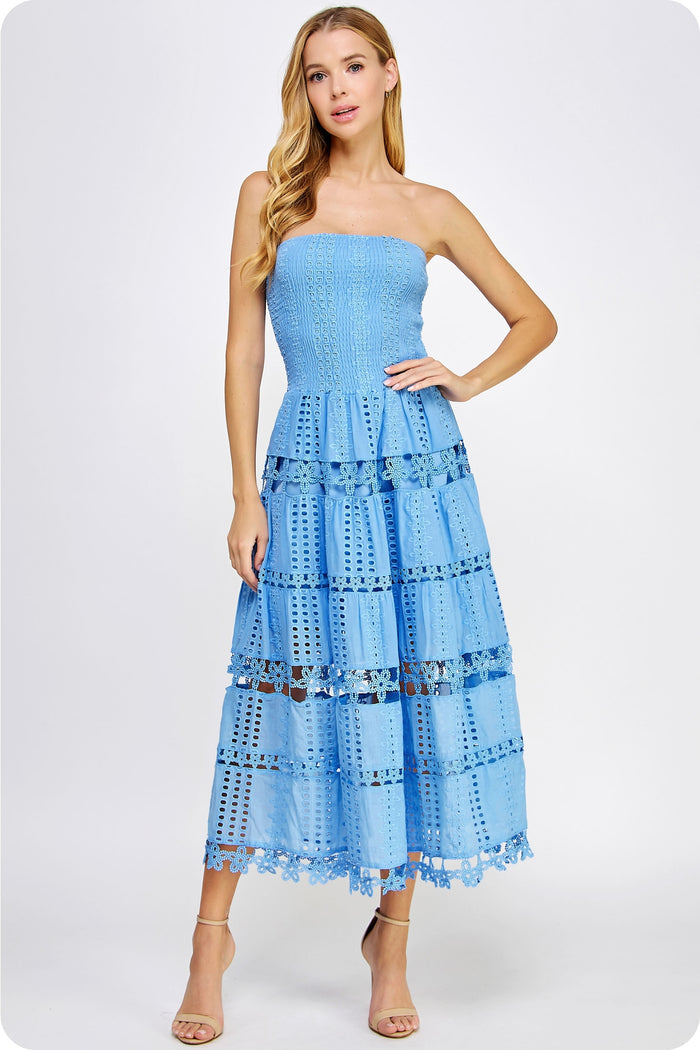 Woman wearing a light blue strapless dress with ruffled layers on a white background