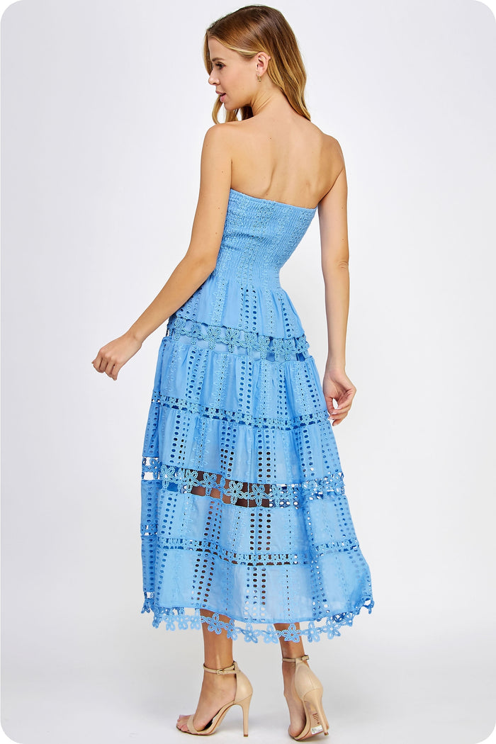 Woman wearing a light blue strapless dress with ruffled layers on a white background