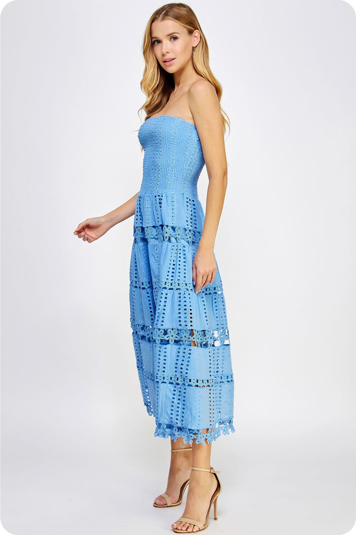 Woman wearing a light blue strapless dress with ruffled layers on a white background