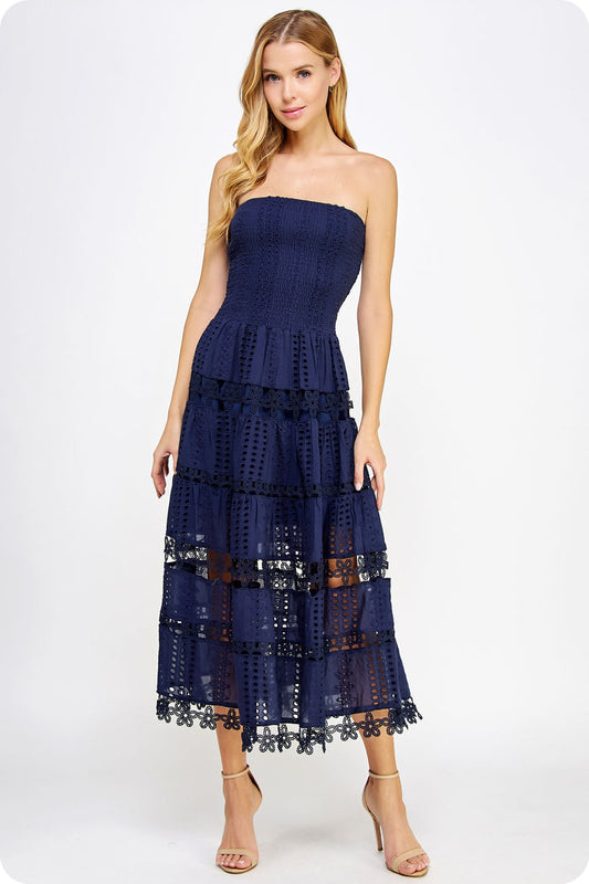Woman wearing a navy strapless dress with lace details on a white background