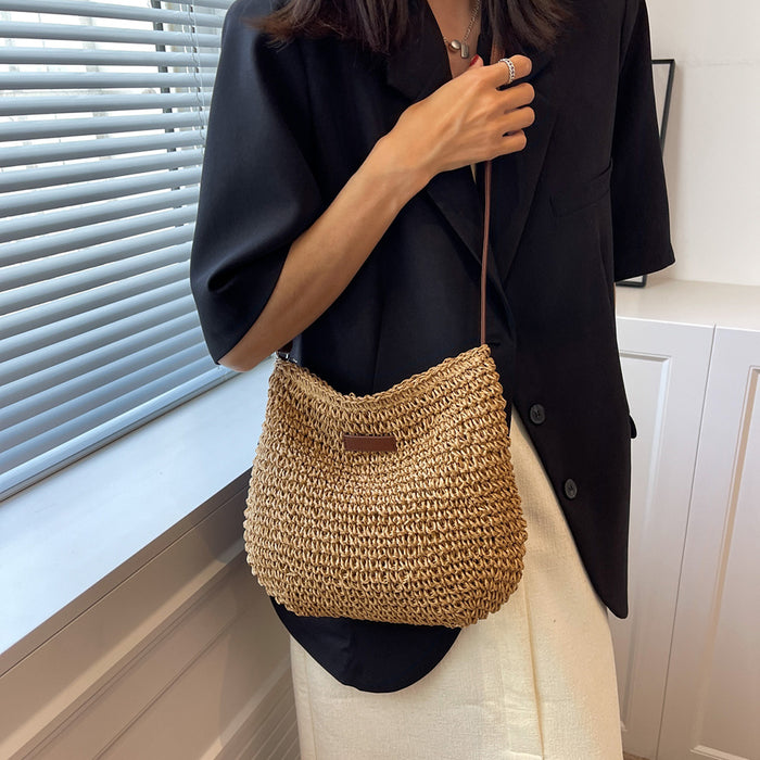 Person holding a woven handbag in a room with a window and white cabinets.