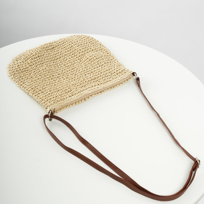 Woven beige handbag with a brown strap on a white surface