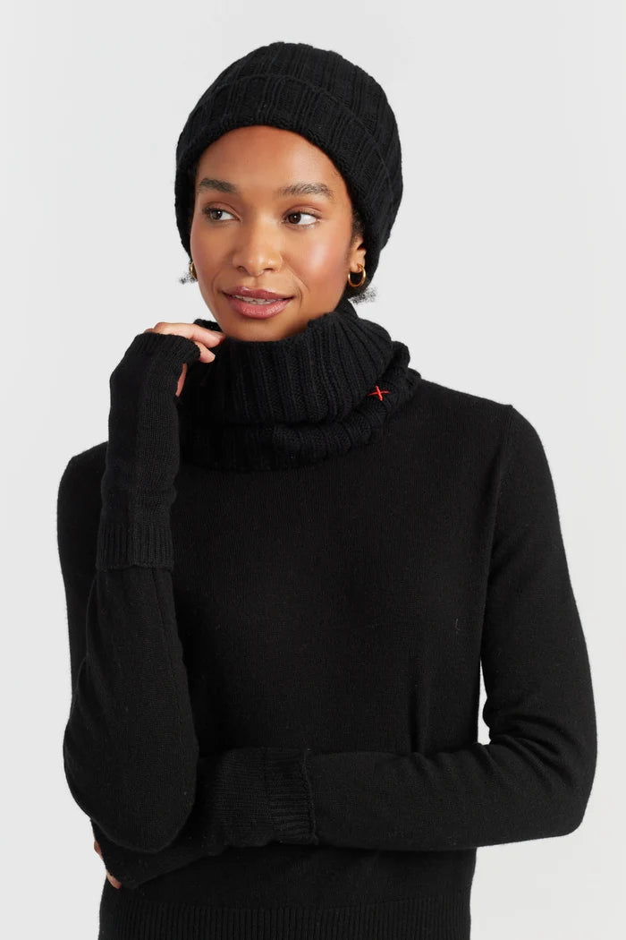 Woman wearing a black knit sweater and beanie against a white background
