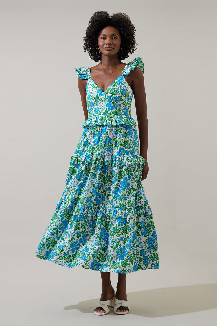Woman wearing a blue and green floral dress with puffy straps on a plain background