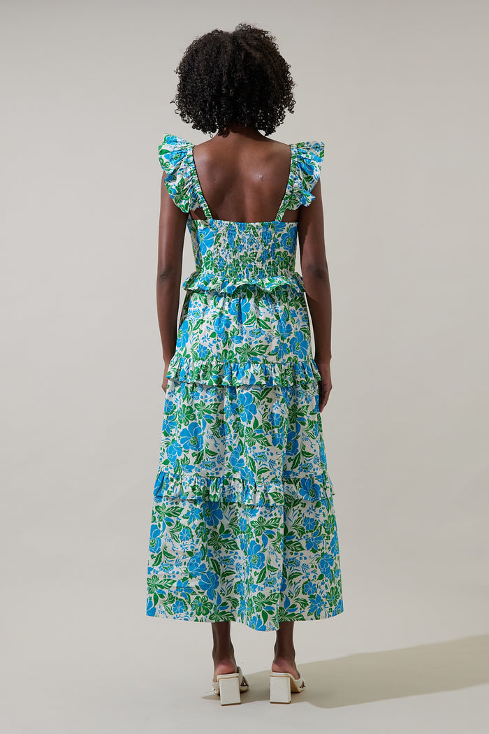 Woman wearing a blue floral dress with leg slit and puffy straps against a plain background
