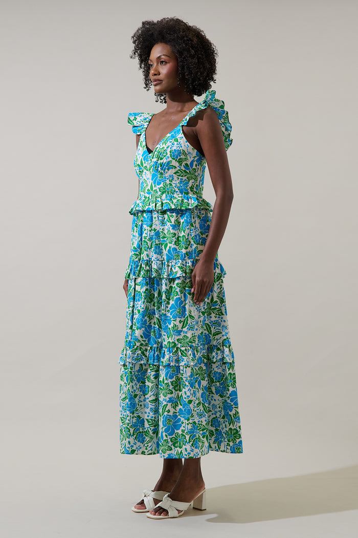 Woman wearing a blue floral dress with leg slit and puffy straps against a plain background