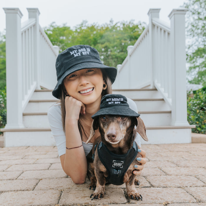 A woman and her brown dachshund relax together in matching Sassy Woof Bucket Hat Bundle - BFF hats—hers reads “MY DOG IS MY BFF” and her pup’s says “MY MOM IS MY BFF.”.