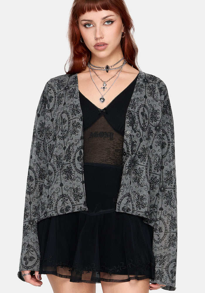 Woman wearing a black patterned cardigan over a black outfit on a white background