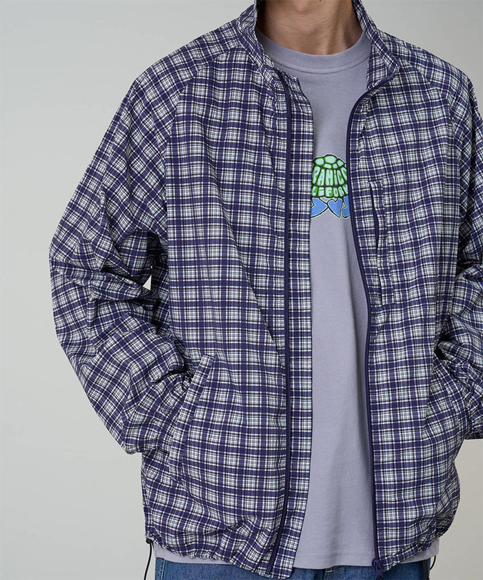 Model wearing a Gramicci navy Checkered Shell Jacket against a light-tone background.