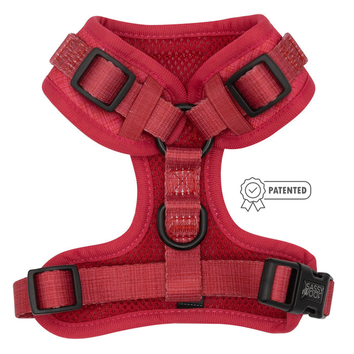 The Sassy Woof Dog Adjustable Harness - Merlot features red padding, adjustable straps, black plastic buckles, a metal D-ring, and a patented label on the right side. The harness is shown flat on a white background.