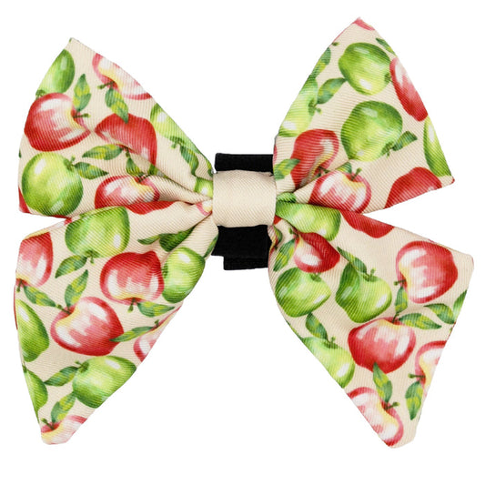 The "Dog Sailor Bow - Apple of My Eye" by Sassy Woof features a red and green apple pattern on cream and a black band—perfect for pairing with your dog's harness or modern pet accessories.
