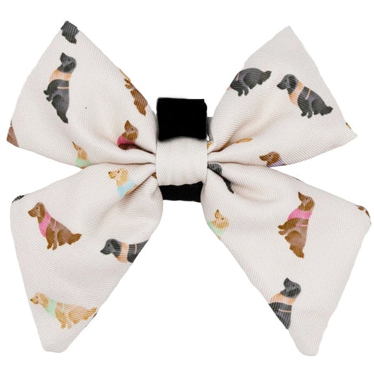 The Sassy Woof Dog Sailor Bow - Loyal Labradors is a white bow tie with playful labrador prints in sweaters and a black center band, perfect for clipping onto your dog's collar or harness.