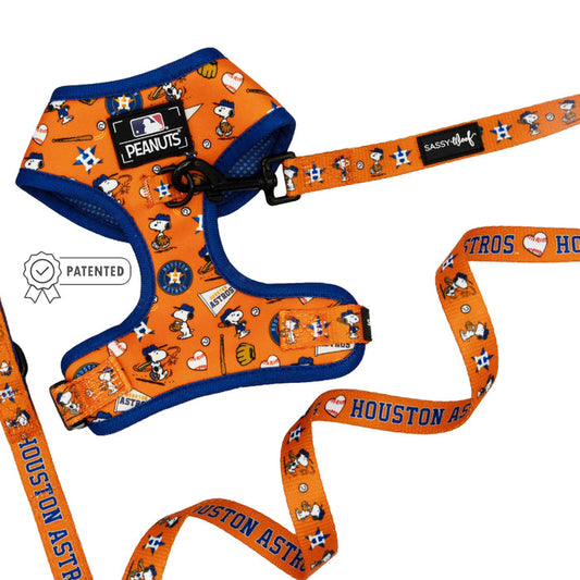 The Sassy Woof Dog Two Piece Bundle - MLB™ x Peanuts™ Houston Astros™ includes an orange and blue dog leash and Snoopy harness with Peanuts characters, baseball icons, hearts, Astros logos, adjustable straps, and a “Patented” badge on the left.