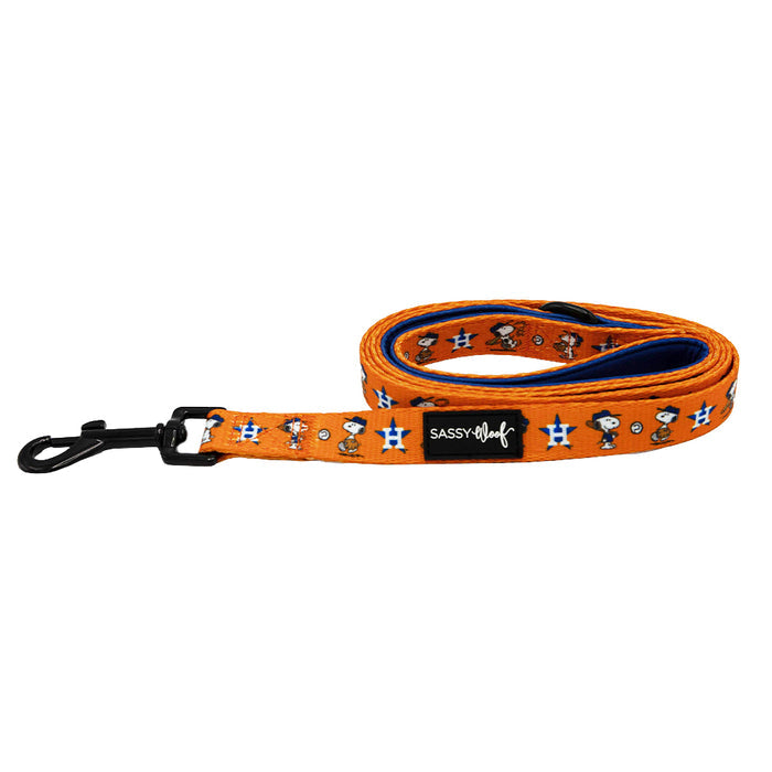 The Sassy Woof Dog Two Piece Bundle - MLB™ x Peanuts™ Houston Astros™ features a vibrant dog leash with cartoon dogs, blue stars, a SASSY WOOF tag, and black metal clip. Coiled neatly, it perfectly complements the matching Snoopy harness for fun walks.