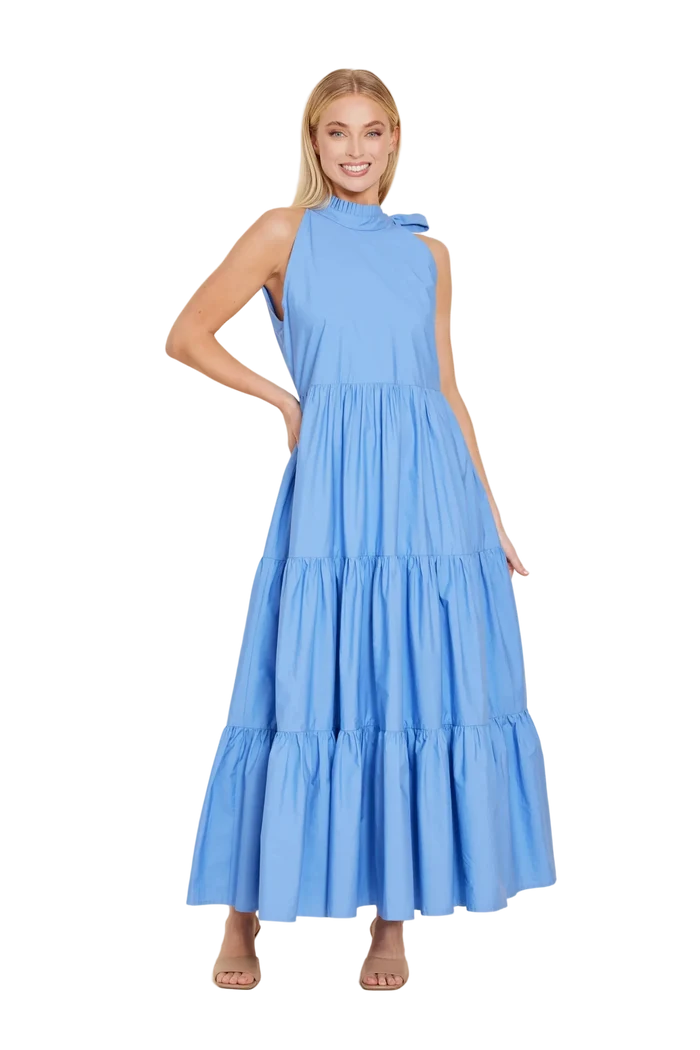 Woman wearing a blue tiered dress against a beige background