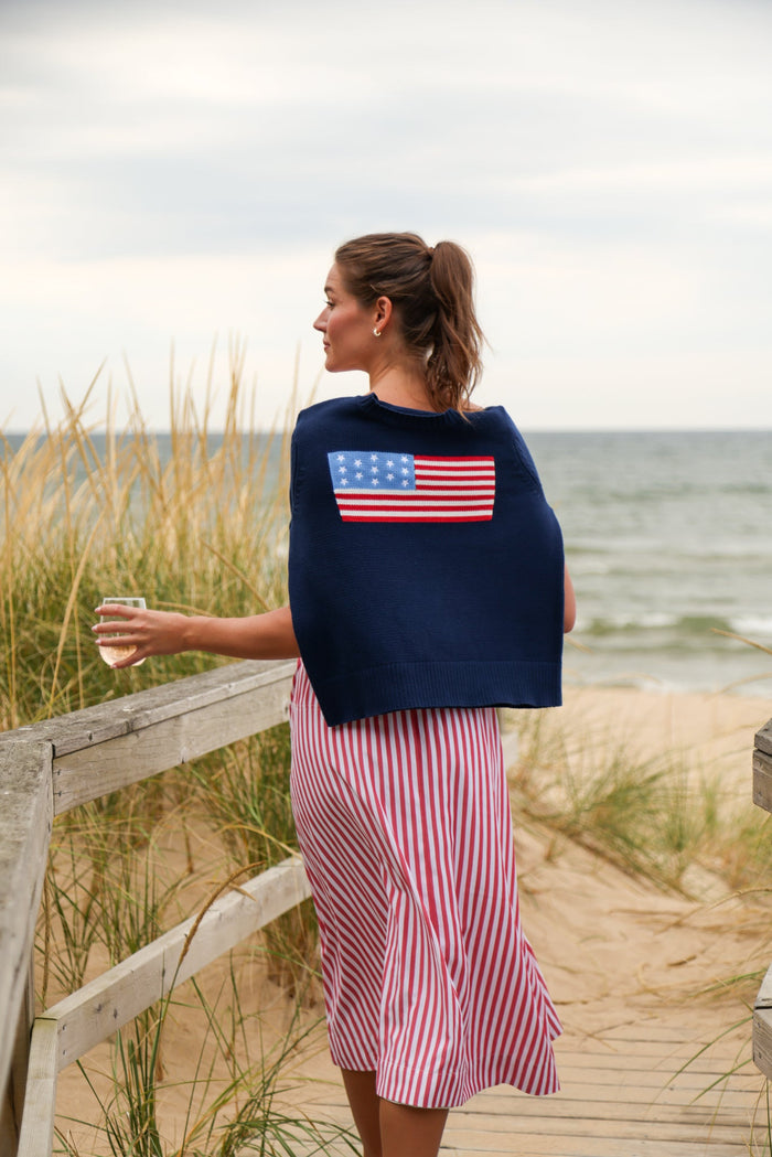 Woman wearing navy sweater with US flag design on a beach background