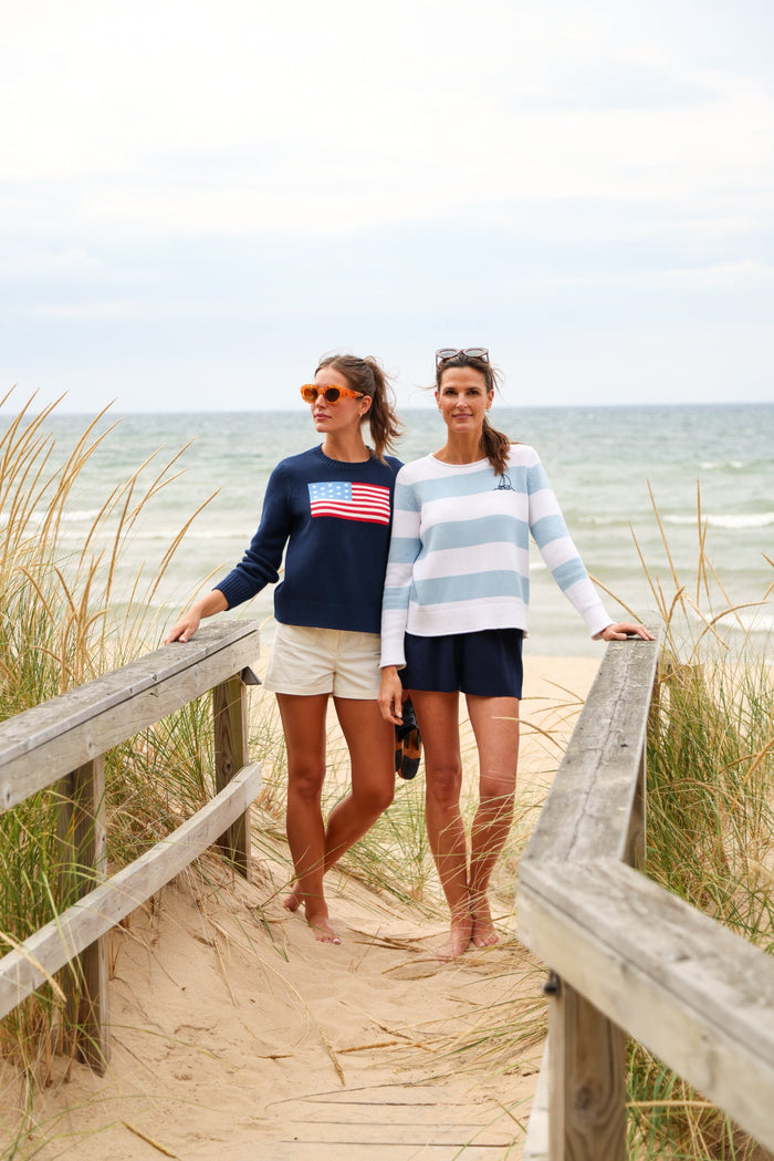 Woman wearing navy sweater with US flag design on a beach background