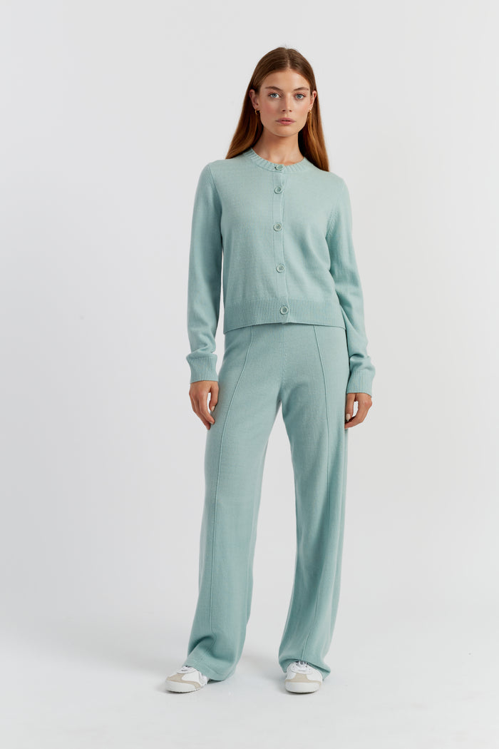 Woman wearing a light green cardigan and pants on a white background