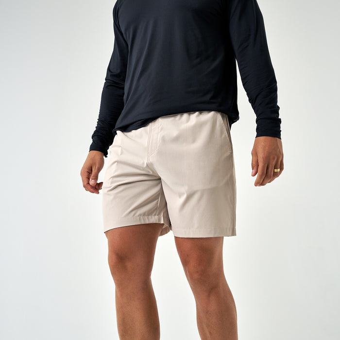 Person wearing beige shorts and a black long-sleeve shirt on a white background