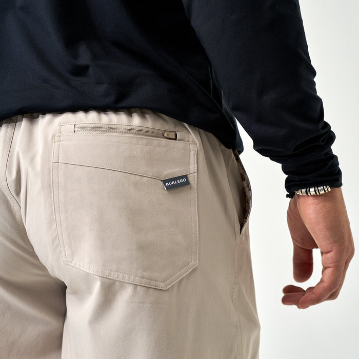 Beige pants with a visible brand label on a white background