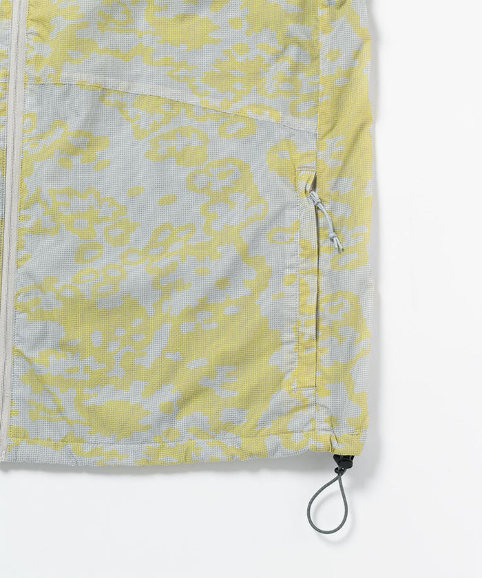 Gramicci yellow and grey grid camo Flyweight Vest hem detail with drawstring against a light-tone background.