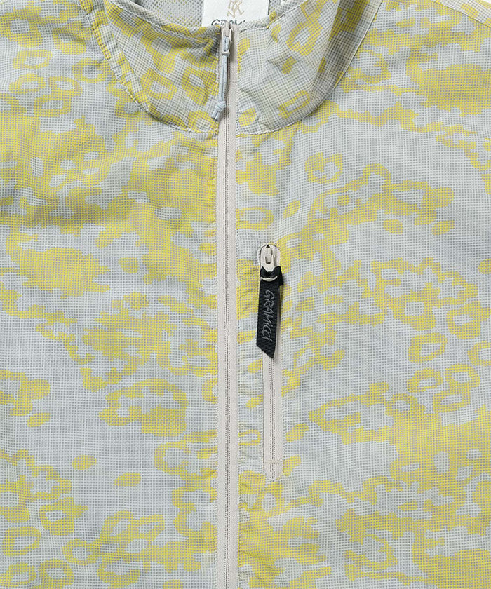 Gramicci yellow and grey grid camo Flyweight Vest collar detail against a light-tone background.