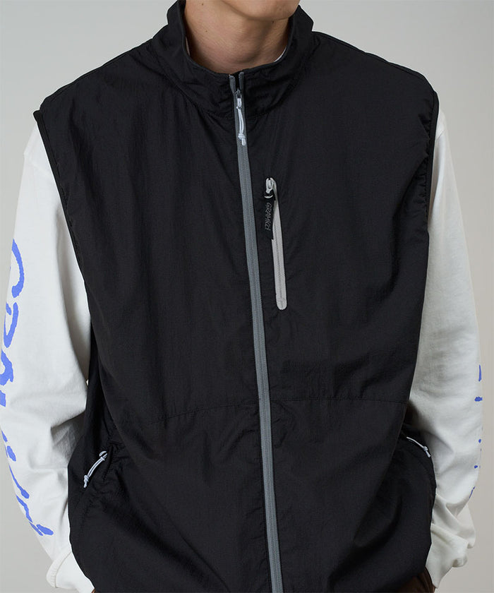 Model wearing a Gramicci black Flyweight Vest against a light-tone background.