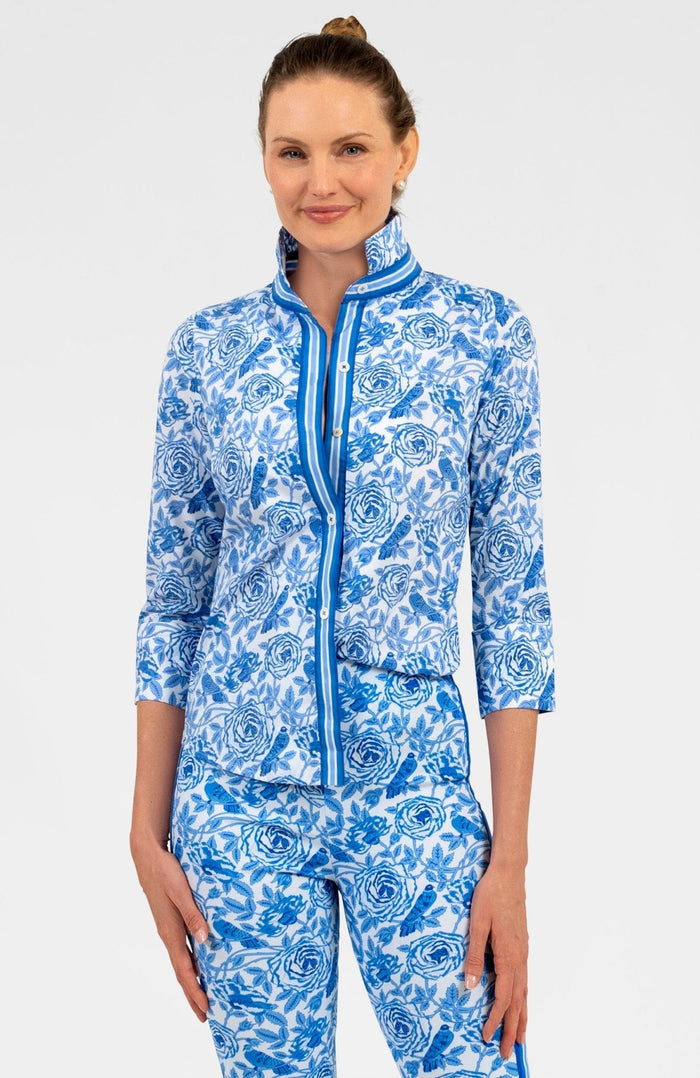 Woman wearing a blue and white patterned shirt with blue trim with matching pants on white background