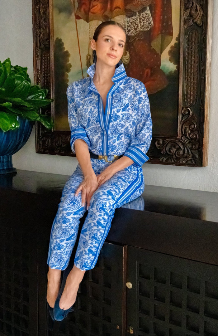 Woman wearing a blue and white patterned shirt with blue trim with matching pants indoors