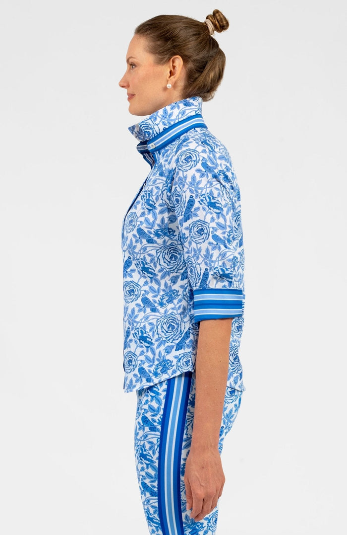 Woman wearing a blue and white patterned shirt with blue trim with matching pants on white background