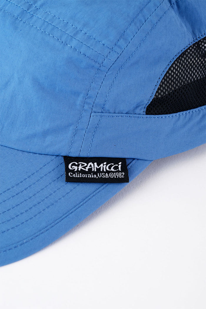 Close-up of Gramicci Guide Cap in the color blue against a light-tone background.