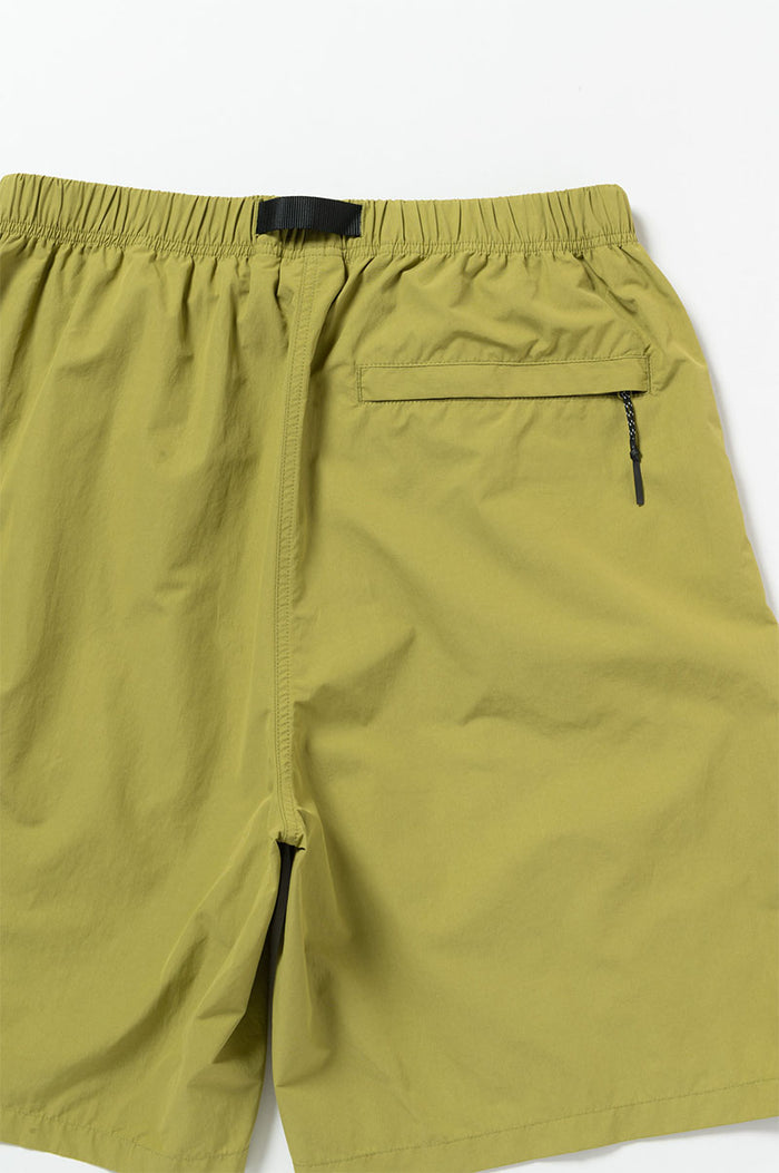 Back view of field green Gramicci Guide Shorts on a light-tone background.