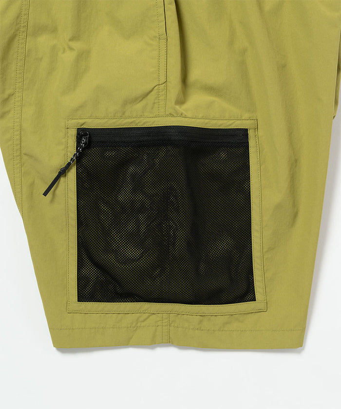 Field green Gramicci Guide Shorts hem showing the logo label on a light-tone background.