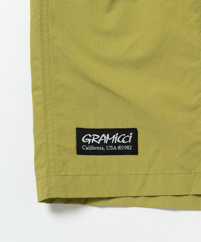 Field green Gramicci Guide Shorts hem showing the logo label on a light-tone background.