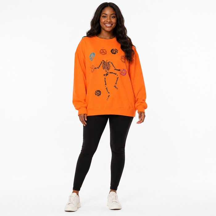 Orange women's Halloween sweatshirt with skeleton pumpkin sequin design, front view, long sleeves and crew neckline on white.