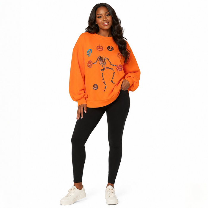 Women's orange skeleton pumpkin sweatshirt with sequin detail at a three-quarter angle, photographed on clean white backdrop.